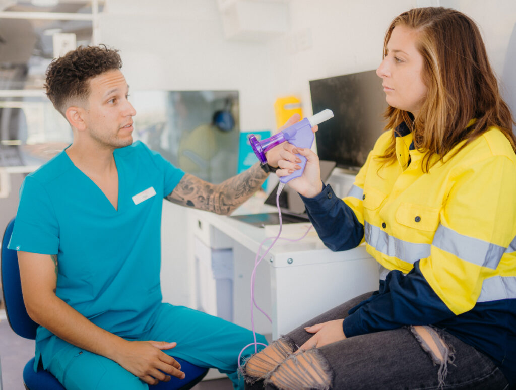 Female worker about to blow into a lung test machine