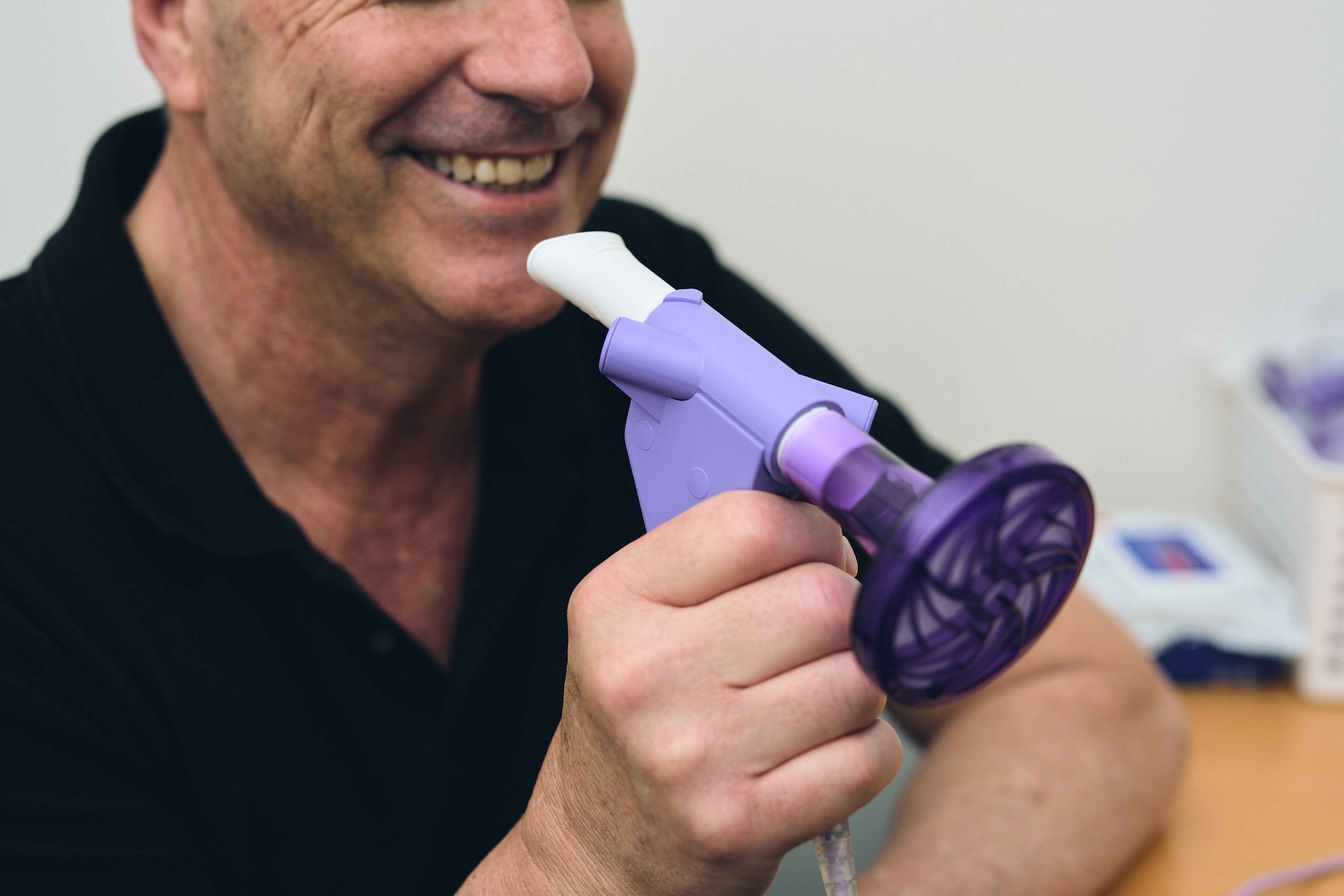 Man holding a spirometry machine, he is smiling