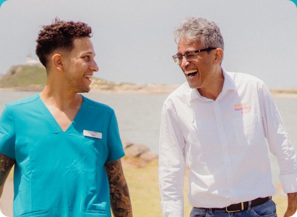 Happy Health CEO and male employee talking with each other and smiling as they walk along a beach
