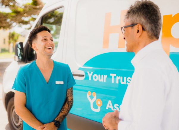 Male occupational health worker chatting to Happy Health CEO and smiling alongside a Happy Health mobile health van