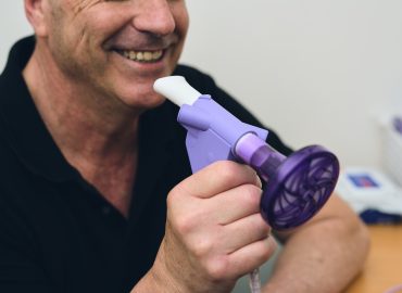 Man holding a spirometry machine, he is smiling